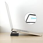 Black Psitek portable laptop cooling stand, made of aluminum, shown elevating a laptop on a desk surface.