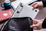 Silver Triyards portable self-adhesive aluminum laptop riser folded and unfolded, attached to a laptop.