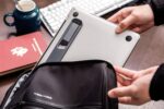 Space Grey Triyards self-adhesive foldable laptop stand attached to the underside of a laptop, elevating it.